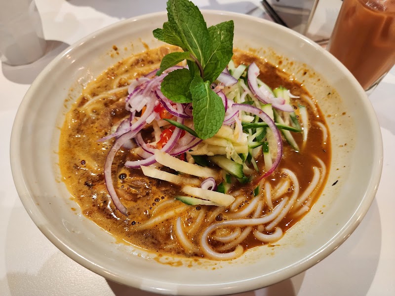 bowl of thick rice noodles in reddish-brown sour asam laksa broth topped with mint, red onion and julienned cucumber â Laksa King Glen Waverley, Glen Waverley