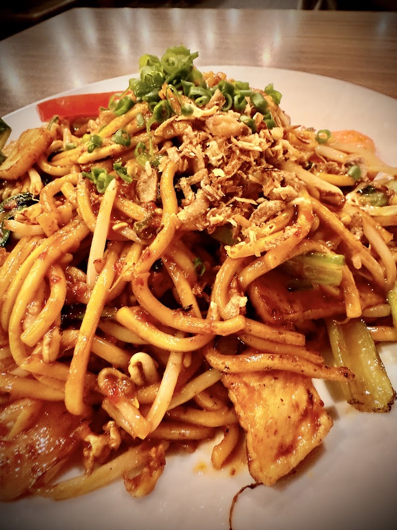 plate of stir-fried Mie Goreng: thick yellow noodles in reddish-brown chilli sauce with bean sprouts, tofu and fried shallots (no fried rice candidate found; this is the noodle half of the topic, no egg visible) â Mamak Melbourne CBD, Melbourne CBD