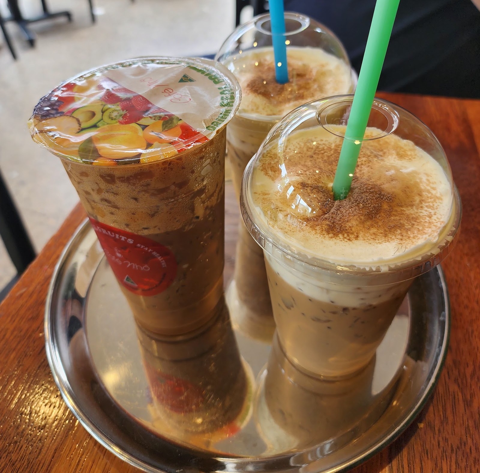 three iced Vietnamese coffees on a steel tray, two capped with salted cream and cocoa dust; cropped to the tray â Cafe Nho, Marrickville